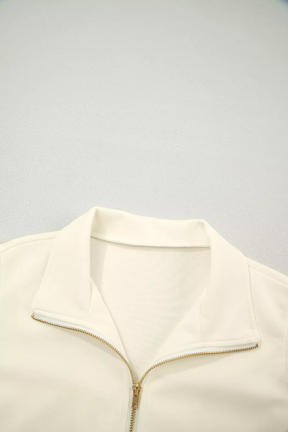 Cream cotton zip blouse with stand-up collar and ruffled detail