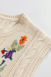 Beige cable knit vest with floral embroidery and open knit details.