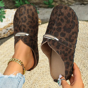 Brown leopard print slip-on flats with decorative buckle detail and side cutouts.