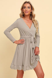 Tan wrap dress with long sleeves, V-neck, tie waist, and ruffled hem.