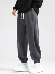 Dark gray relaxed fit sweatpants with white drawstring and cuffed ankles.