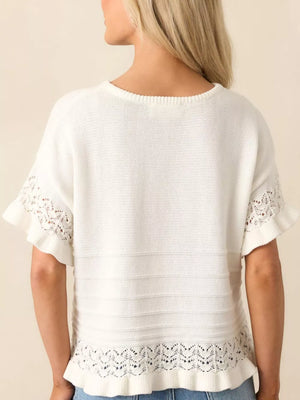 White knit top with crew neck, short sleeves, and delicate lace trim at hem and cuffs.