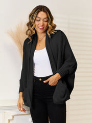 Black acrylic knit cocoon cardigan with shawl collar and pockets.