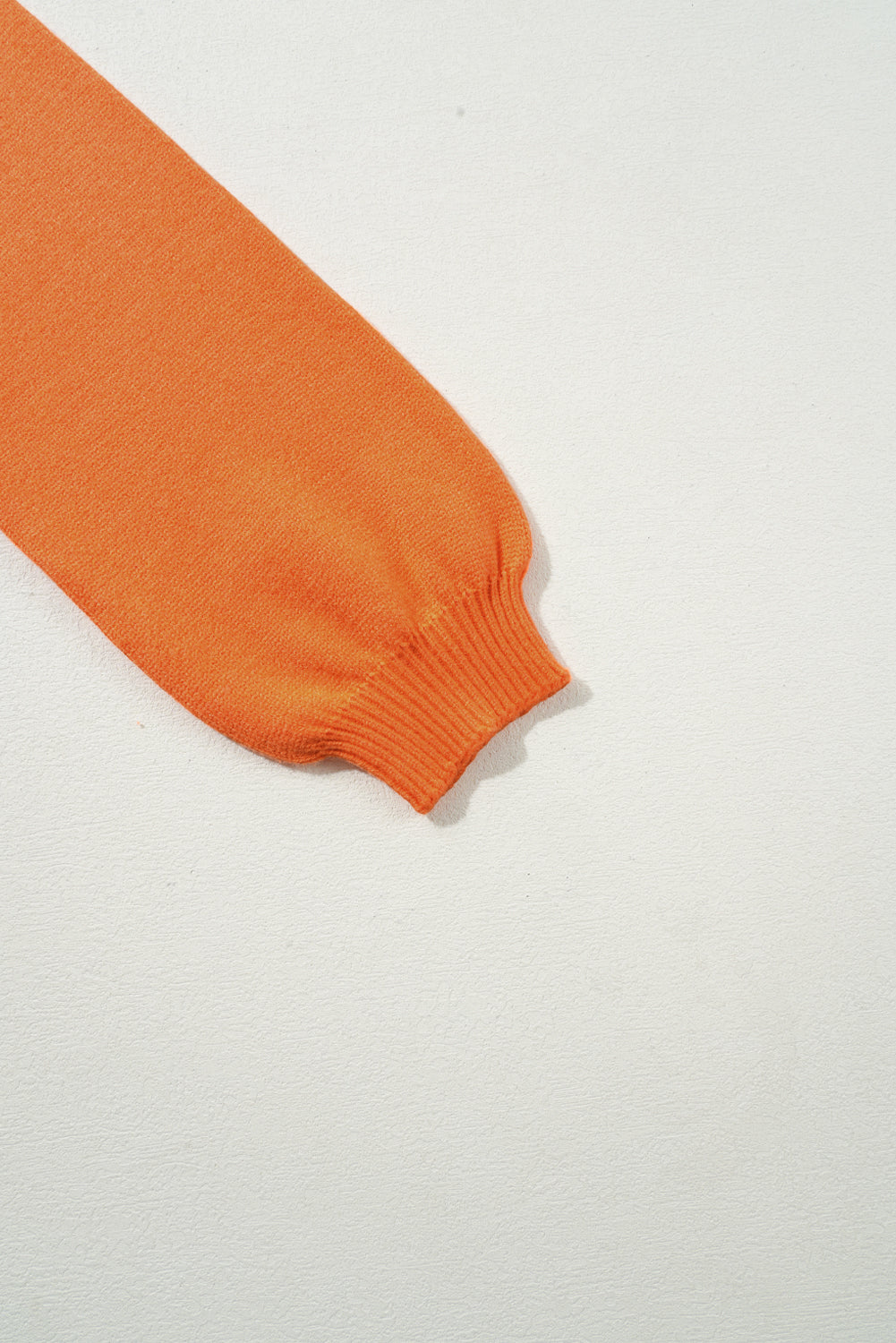Orange knit sweater sleeve with ribbed cuff detail