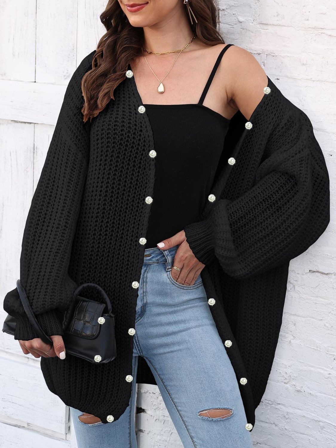 Black balloon sleeve cardigan with pearl buttons and open knit detail.