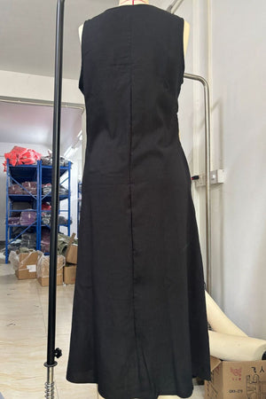 Black asymmetrical button-down midi dress with a sleeveless cut and A-line skirt.