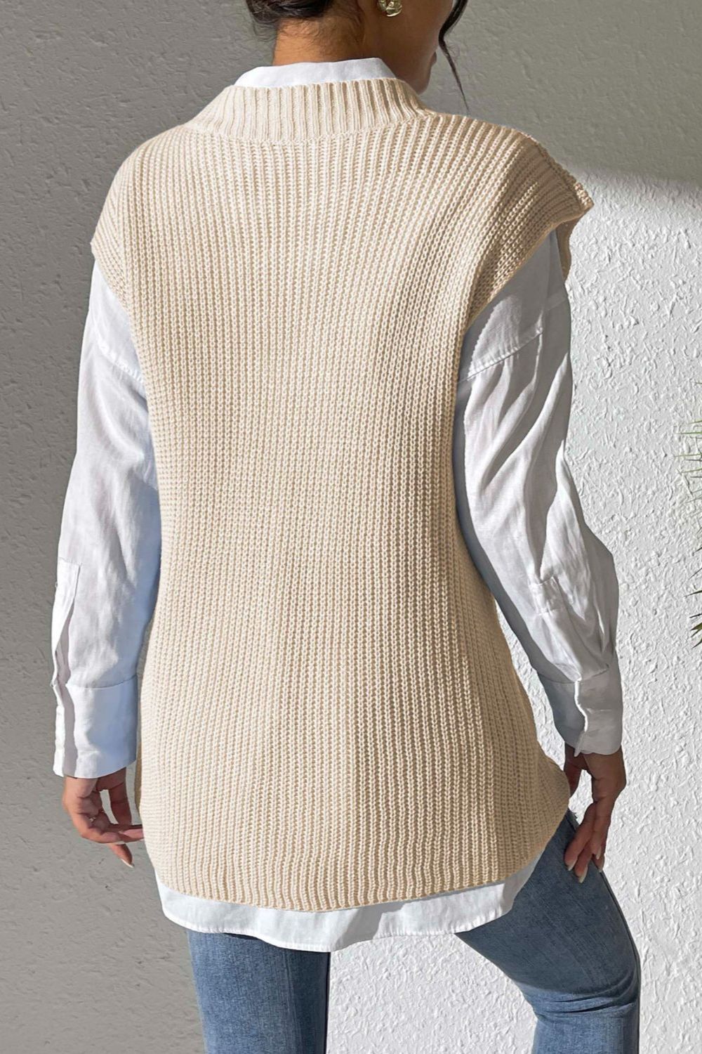 Beige textured knit V-neck sleeveless top with ribbed detail, styled over a white shirt.