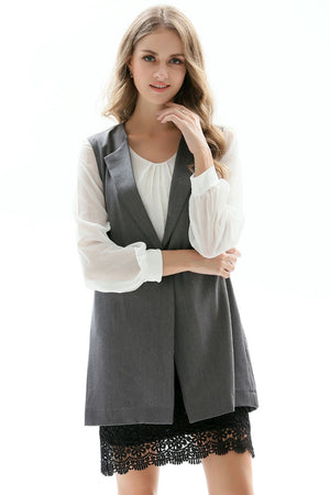 Tailored sleeveless vest in mid gray with single button closure, worn over a white blouse and black lace skirt.
