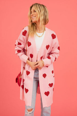 Blush pink acrylic longline knit cardigan with red heart motif and pockets.