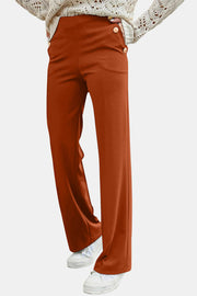 Button detail wide leg trousers in caramel, styled with a cream sweater and sneakers.