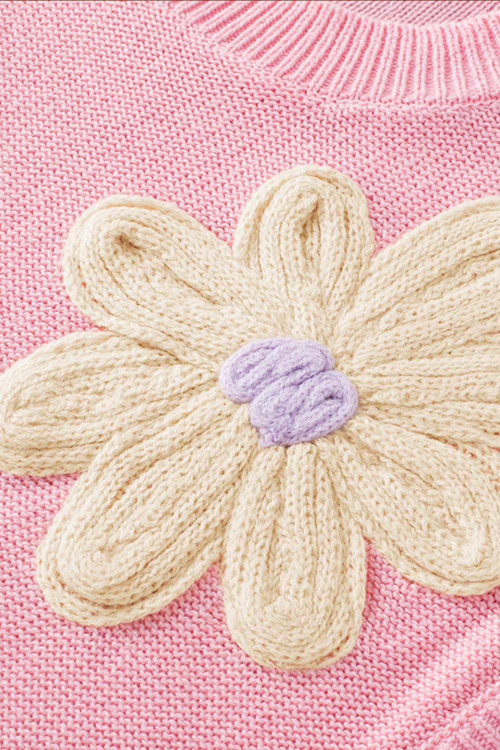 Knit sleeveless top in pink with a cream floral embroidery detail and lavender center.