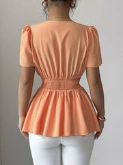 Orange polyester peplum blouse with smocked waist and puff sleeves.