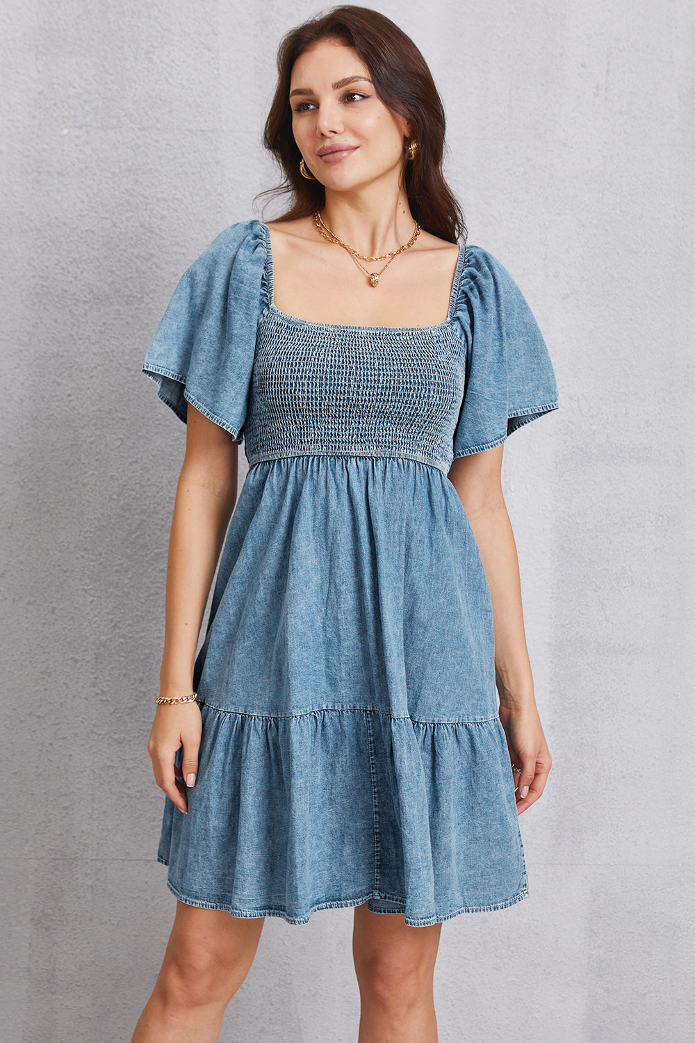 Light blue denim prairie dress with square neckline, smocked bodice, puff sleeves, and tiered skirt.
