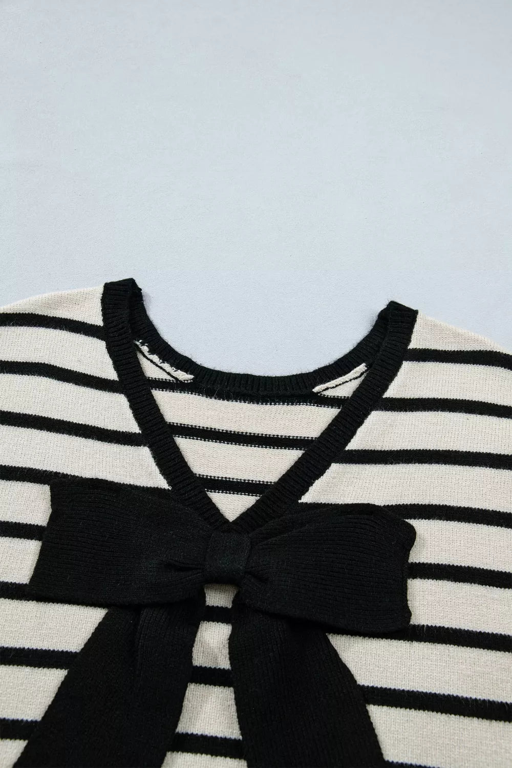 Black and white striped knit cardigan with V-neck and black bow detail.