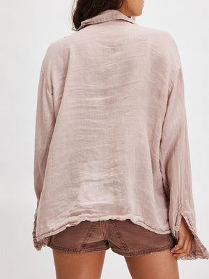 Dusty pink linen button-down blouse with ruffled hem and button cuff detail.