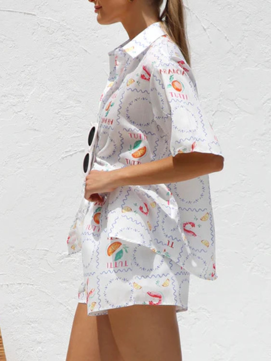 White resort set with citrus and tutti frutti print, button-up shirt and shorts.