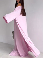 Blush pink off-the-shoulder maxi dress with long sleeves and high slits, styled with a grey bag.