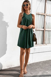 Forest green sleeveless trapeze dress with pleated yoke detail.