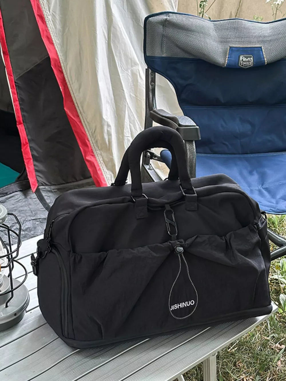 Black crinkled nylon drawstring travel bag with side pockets and top handles.
