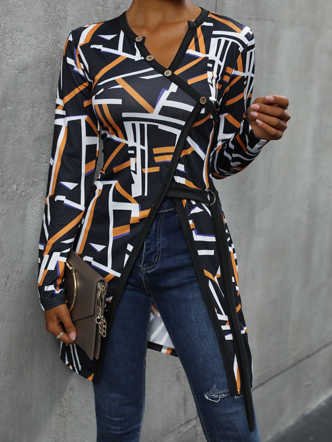 Black geometric asymmetric blouse with decorative buttons and wrap detail.
