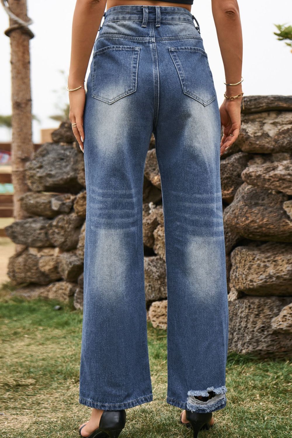 Distressed wide-leg denim trousers in medium wash with frayed hem detail.