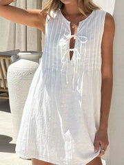 White tie-front mini dress with vertical pintuck details and a keyhole neckline.