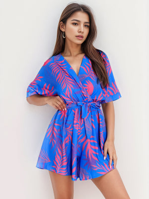 Blue tropical print wrap romper with tie waist and short sleeves.