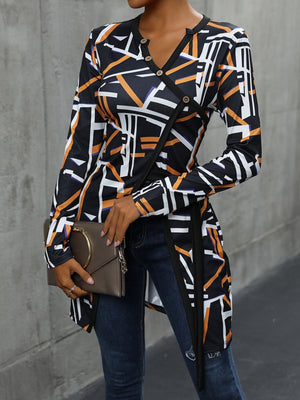 Geometric print asymmetric black blouse with decorative buttons and wrap detail.