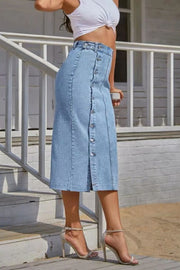 Light denim midi skirt with button front and slit, styled with heels.