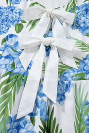 Ruffled mini dress with hydrangea and palm print, featuring white bow details.