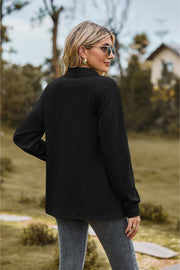 Black textured knit polo shirt with a collared neckline and long sleeves.