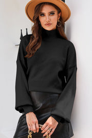 Black knit sweater with mock neck and balloon sleeves, ribbed cuffs.