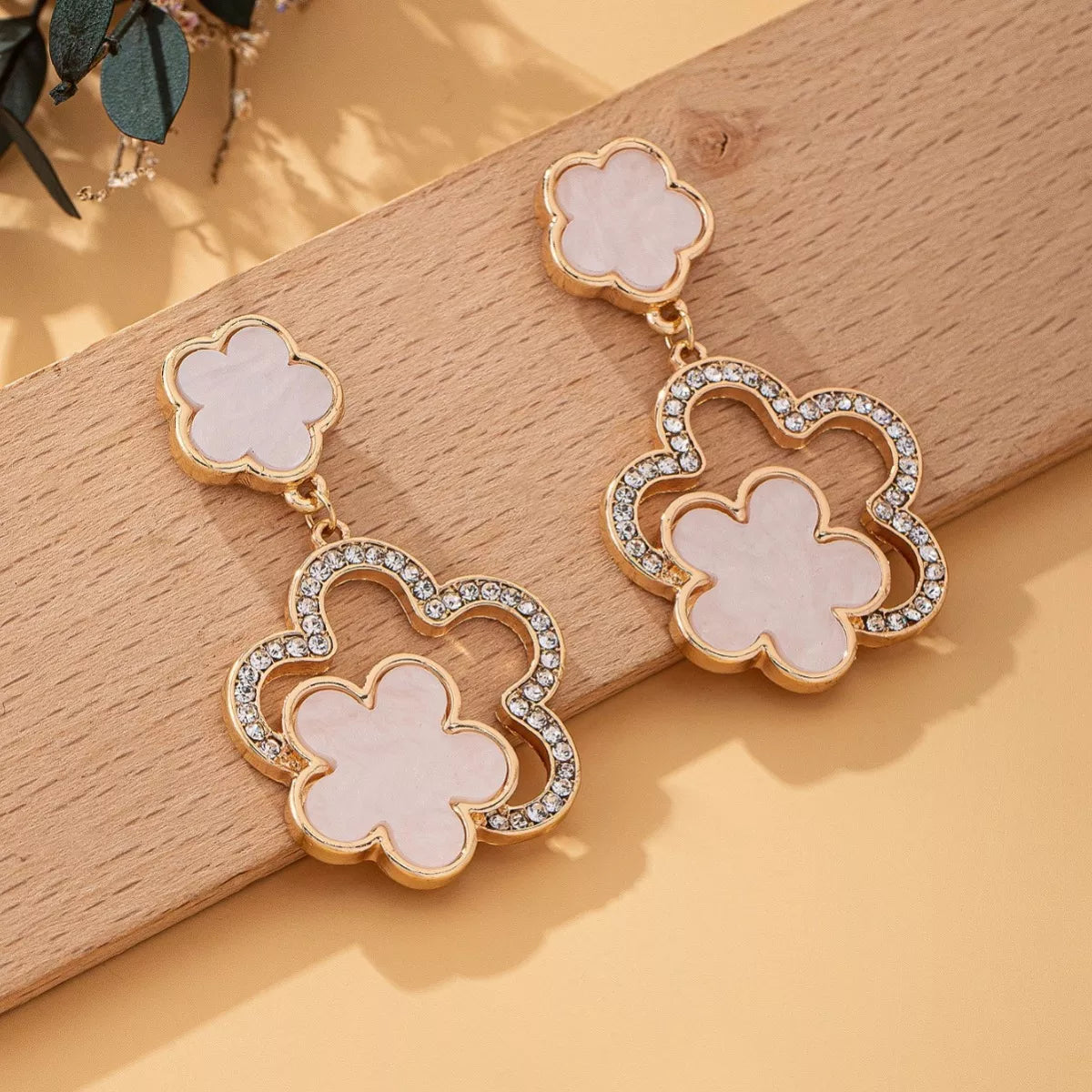 White clover dangle earrings with 18K gold plating and crystal accents.