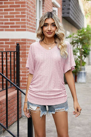 Pink perforated dolman sleeve blouse with V-neck and side ruching.