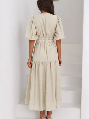 Cream midi dress with puff sleeves, cinched waist, and tiered skirt.