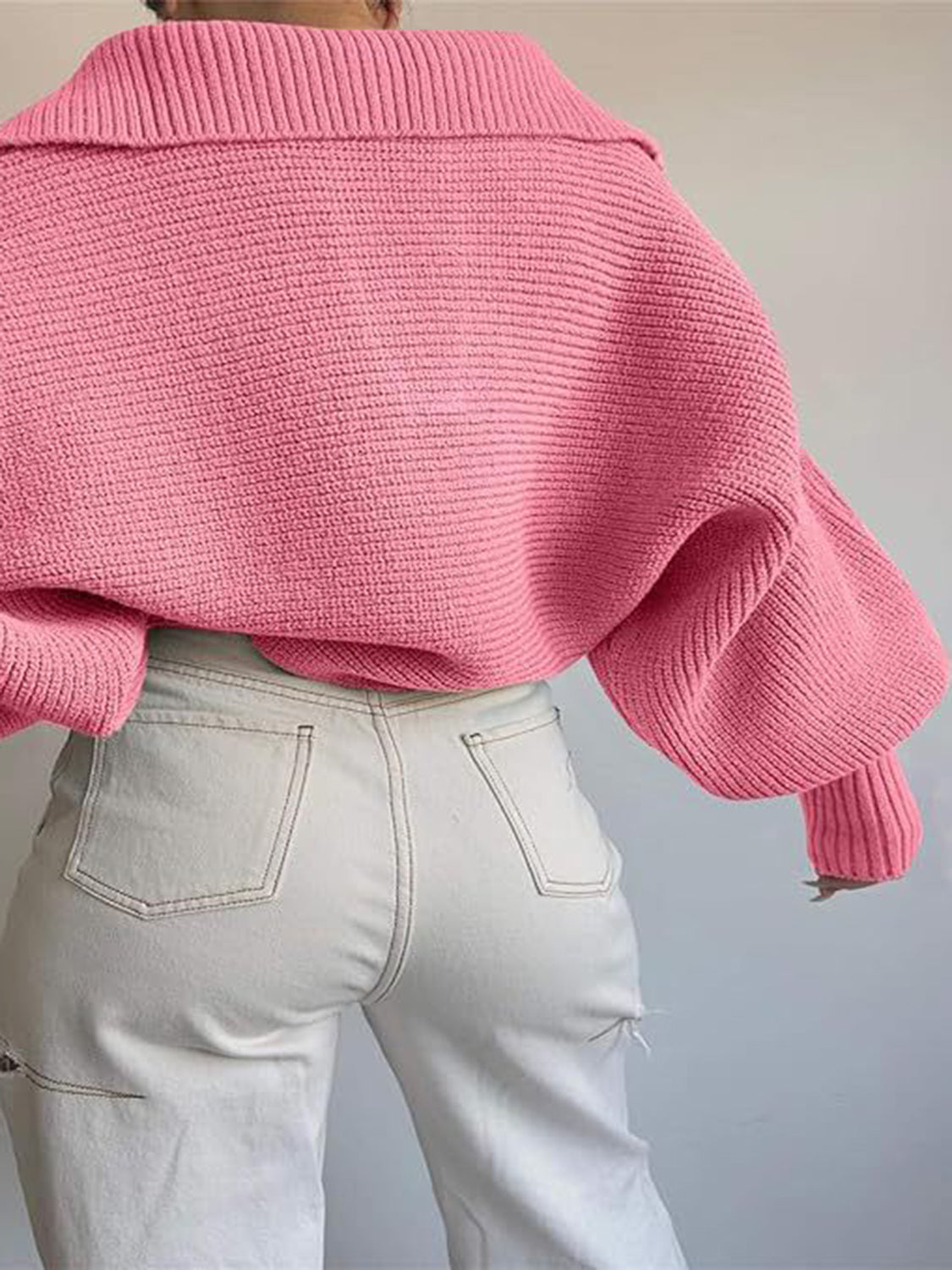 Pink knit sweater with wide collar and balloon sleeves, paired with light wash jeans.