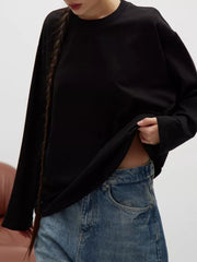 Black oversized crewneck sweatshirt with voluminous sleeves, styled with jeans.