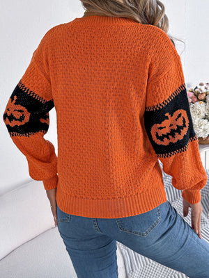 Orange acrylic knit sweater with black intarsia jack-o'-lantern sleeves and a textured knit body.