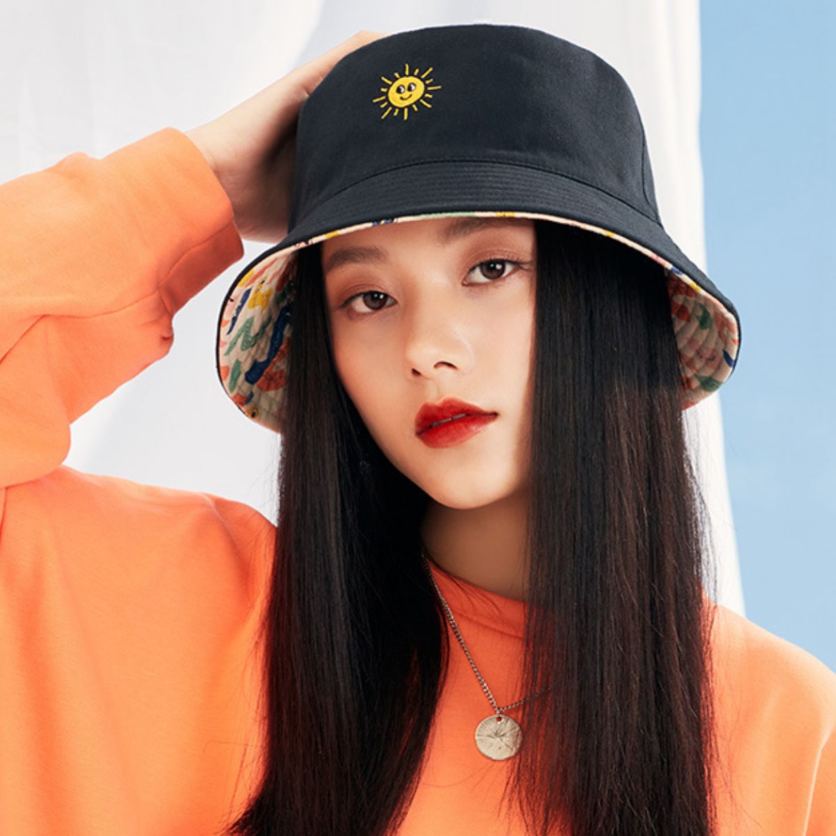 Black bucket hat with embroidered sun detail and colorful abstract print lining