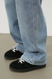 Oversized fade wash denim jeans in medium blue, shown with black sneakers.