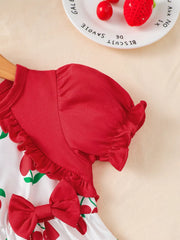 Baby dress with cherry print, red ruffled sleeves, and a red bow detail.