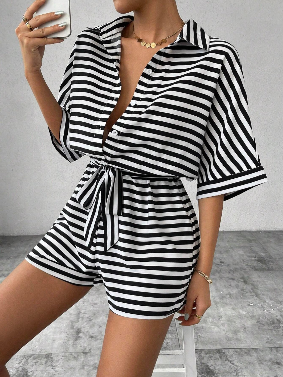 Black and white striped shirt romper with self-tie belt and button front.
