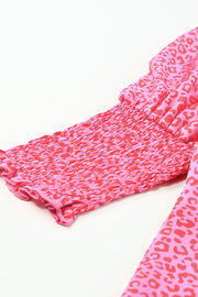 Pink leopard print blouse with smocked cuffs and sleeves.