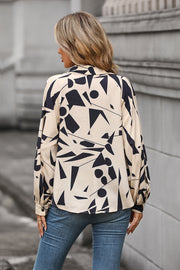 Cream geometric print blouse with voluminous sleeves and button cuffs.