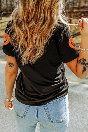 Black cotton t-shirt with glitter pumpkin motif on sleeves.