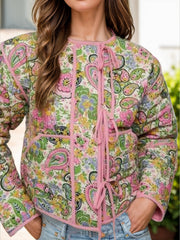 Paisley quilted jacket with tie closure in blush pink with pink trim and a floral pattern.