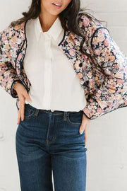 Floral quilted jacket with contrast piping and button front, worn over a white shirt and jeans.