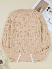 Beige acrylic V-neck knit sweater with wavy openwork pattern and white lace trim at cuffs.