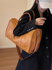 Cognac vintage leather duffle bag with top handles and adjustable strap.