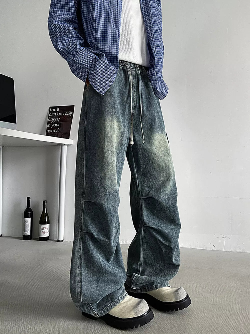 Relaxed fit blue denim cargo jeans with drawstring waist and visible stitching details.
